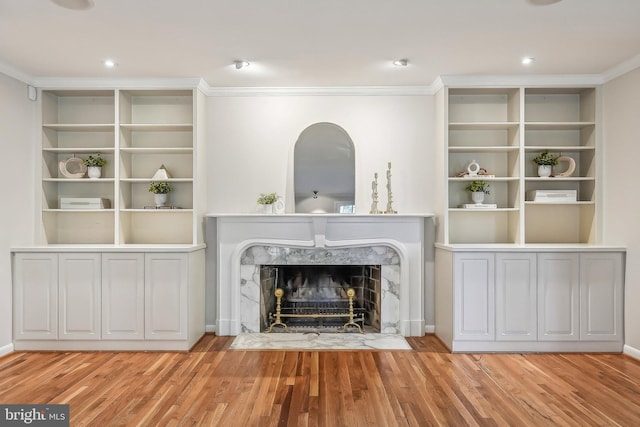 unfurnished living room featuring recessed lighting, wood finished floors, a high end fireplace, and crown molding