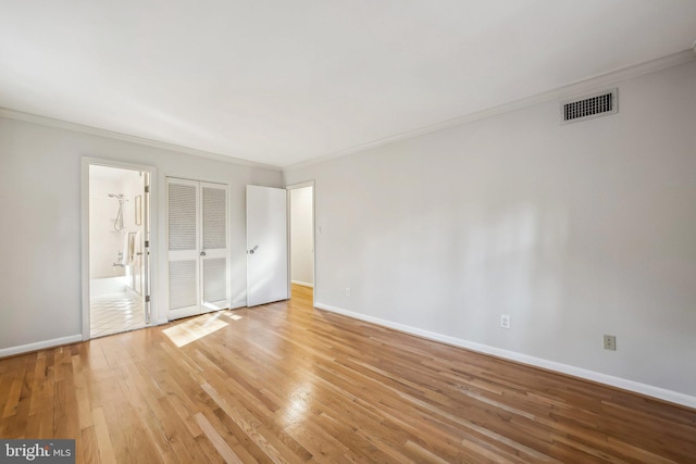 unfurnished bedroom featuring baseboards, visible vents, ornamental molding, ensuite bathroom, and light wood-type flooring