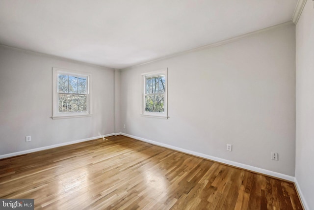 empty room featuring crown molding, baseboards, and wood finished floors