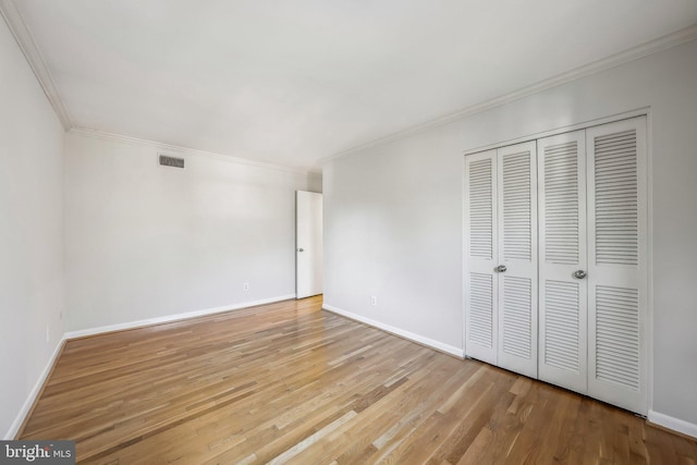 unfurnished bedroom with visible vents, a closet, light wood-style floors, crown molding, and baseboards