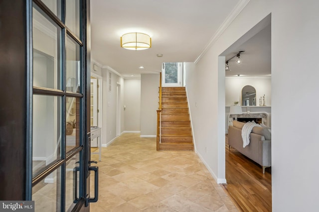 entrance foyer with a fireplace, stairs, baseboards, and ornamental molding