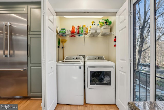 laundry area with laundry area, light wood-style flooring, and washer and clothes dryer