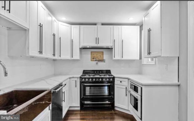 kitchen featuring oven, double oven range, a sink, and white cabinetry