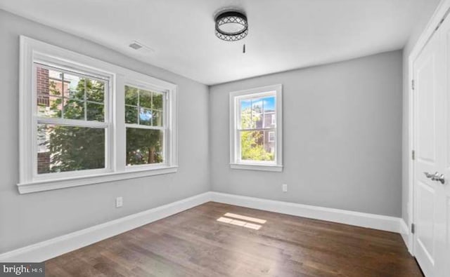 spare room featuring visible vents, baseboards, and wood finished floors