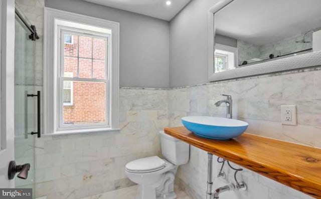 bathroom featuring a sink, tile walls, toilet, and an enclosed shower