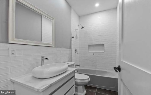 full bathroom featuring shower / bathtub combination, tile patterned flooring, toilet, vanity, and tile walls