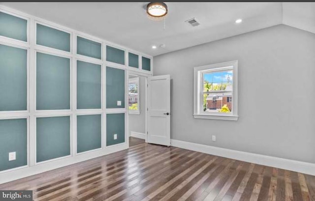 spare room featuring a healthy amount of sunlight, visible vents, and wood finished floors