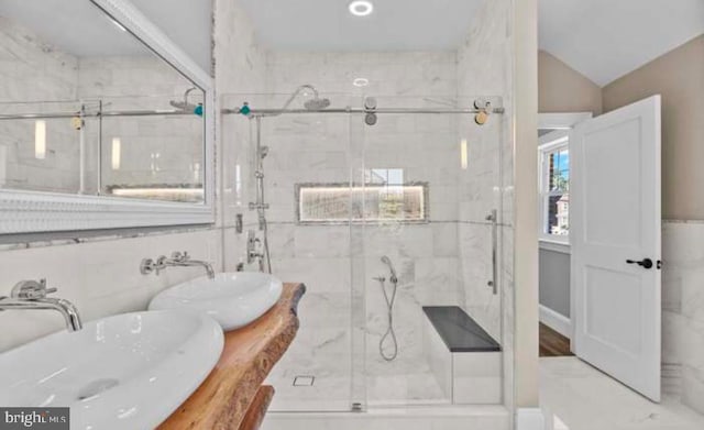 bathroom with lofted ceiling, a marble finish shower, and vanity