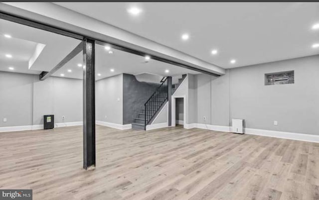 below grade area with light wood-style floors, stairs, baseboards, and recessed lighting