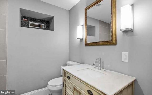 bathroom with vanity, toilet, and baseboards