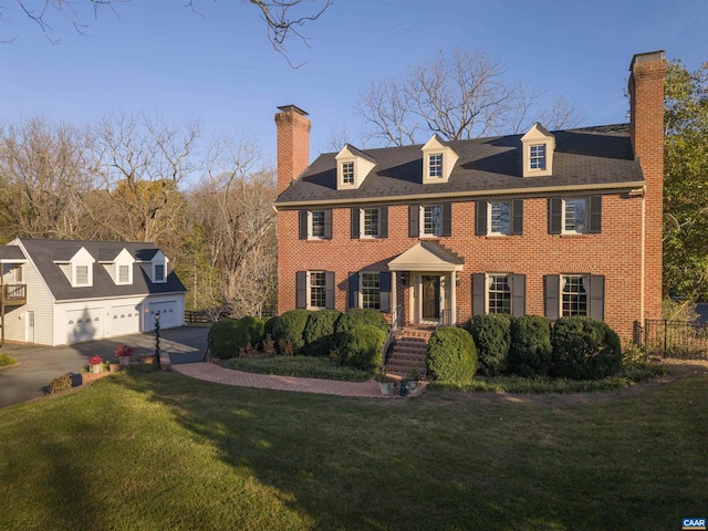 colonial house featuring a garage, brick siding, fence, a front lawn, and a chimney