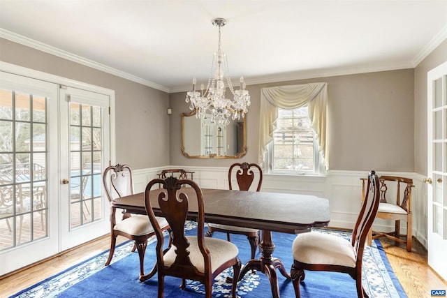 dining area featuring french doors, a wainscoted wall, plenty of natural light, and wood finished floors