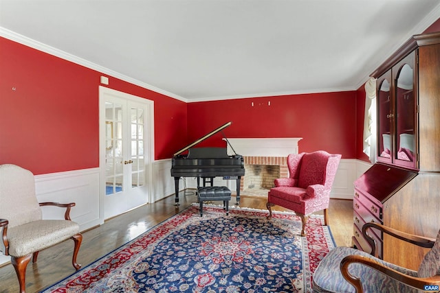 sitting room with ornamental molding, french doors, wainscoting, and wood finished floors