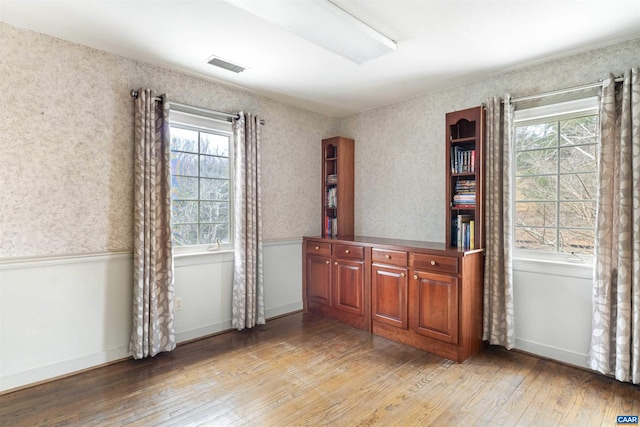 interior space with wainscoting, plenty of natural light, visible vents, and light wood-style floors