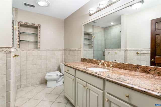 bathroom with visible vents, toilet, tile patterned flooring, a shower stall, and tile walls