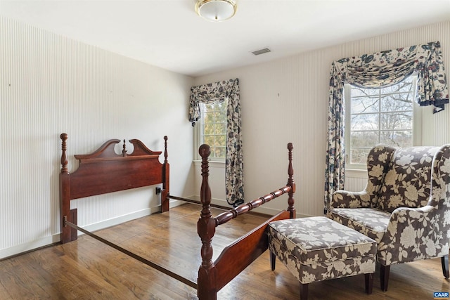 bedroom featuring multiple windows, wood finished floors, visible vents, and baseboards