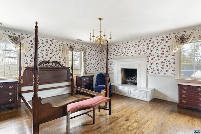 bedroom with visible vents, a high end fireplace, a chandelier, light wood-type flooring, and baseboards