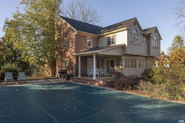 exterior space with brick siding, a patio, and a covered pool