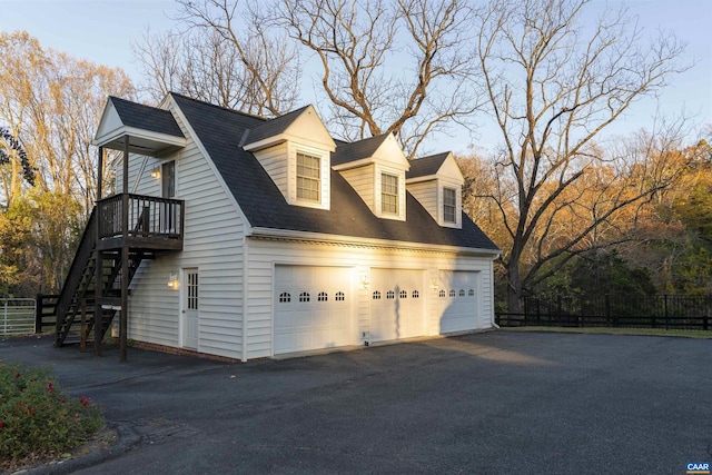 view of home's exterior featuring a shingled roof, stairway, an attached garage, fence, and driveway