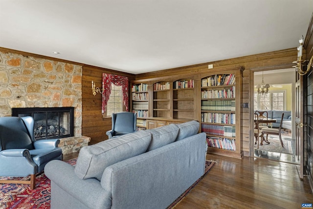 living area with wood walls, a fireplace, a chandelier, and wood finished floors