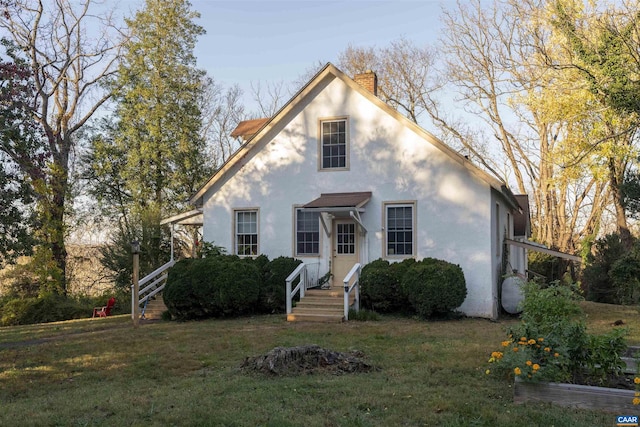 view of front of property featuring a chimney, a front yard, and stucco siding