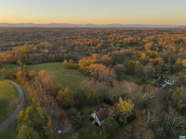 aerial view at dusk with a mountain view and a wooded view