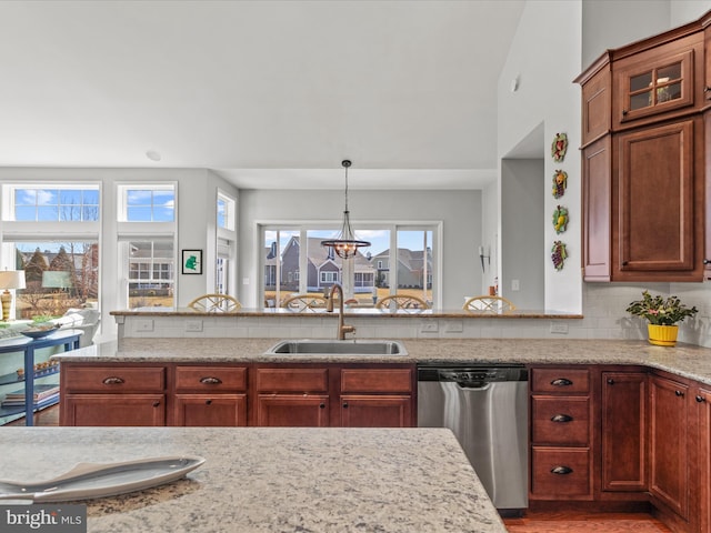 kitchen with light stone counters, a sink, backsplash, a wealth of natural light, and dishwasher