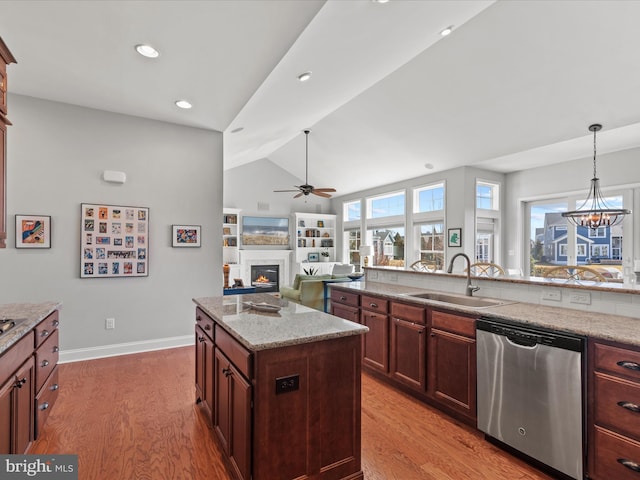 kitchen featuring a sink, light wood finished floors, stainless steel dishwasher, and a glass covered fireplace