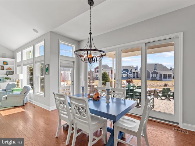 dining room with a notable chandelier, hardwood / wood-style floors, visible vents, and baseboards