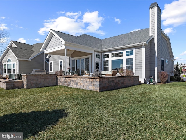 rear view of house featuring a yard, a patio, a chimney, a shingled roof, and area for grilling