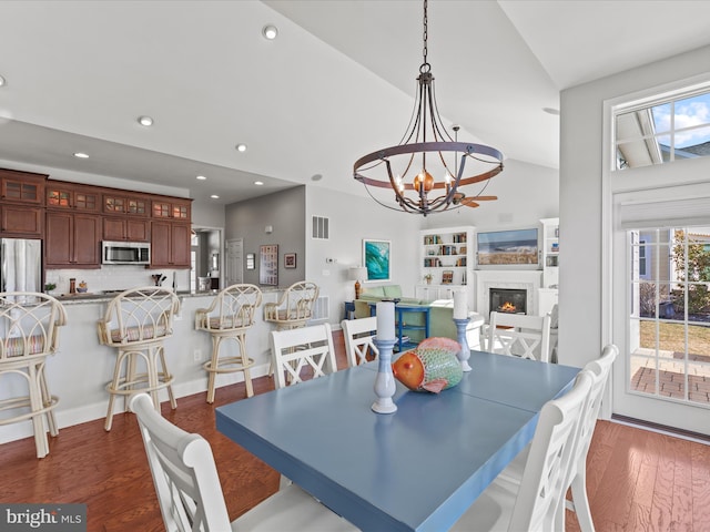 dining space featuring a chandelier, a glass covered fireplace, dark wood-style floors, and a healthy amount of sunlight