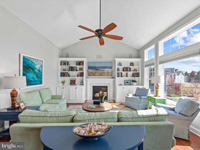 living area featuring ceiling fan, high vaulted ceiling, a fireplace with flush hearth, wood finished floors, and visible vents