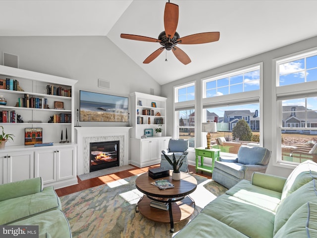 living room with ceiling fan, a fireplace with flush hearth, visible vents, vaulted ceiling, and light wood finished floors