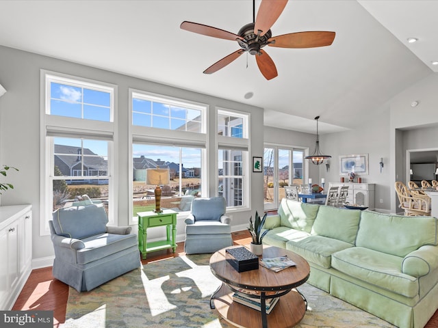 living room with ceiling fan, baseboards, vaulted ceiling, and wood finished floors