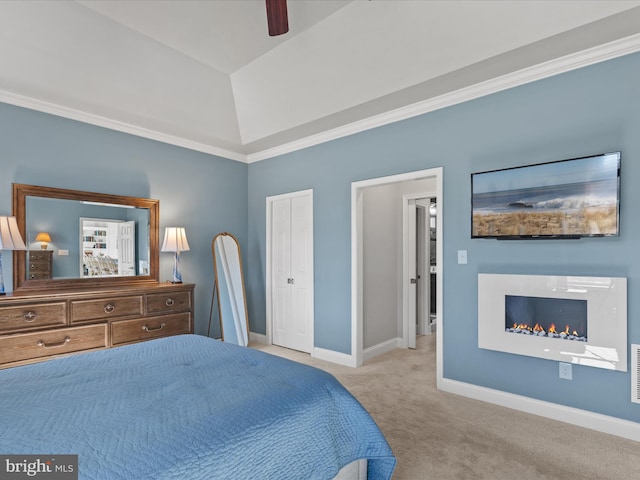 bedroom featuring carpet floors, a ceiling fan, vaulted ceiling, a warm lit fireplace, and baseboards