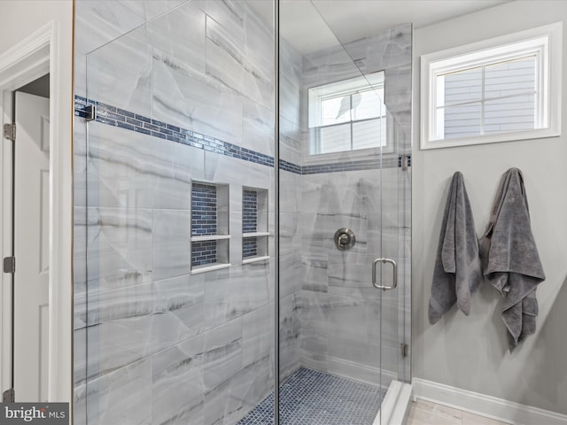 bathroom with a shower stall and baseboards