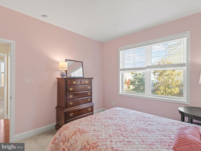 bedroom featuring light carpet and baseboards