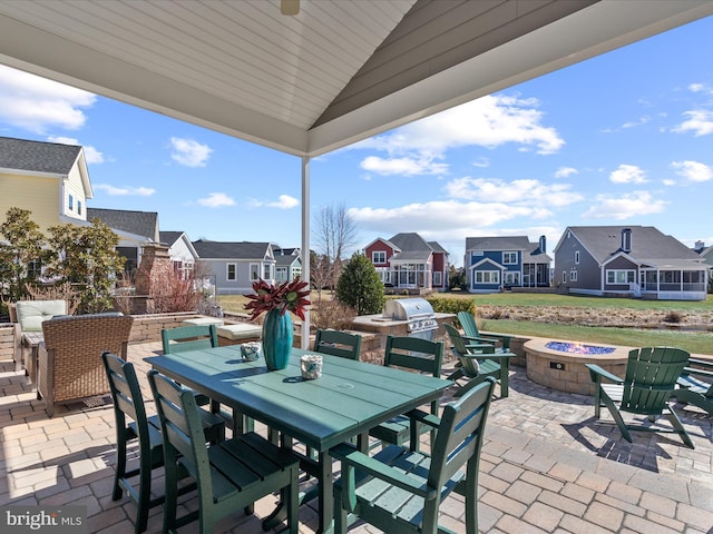 view of patio / terrace with an outdoor fire pit, area for grilling, exterior kitchen, a residential view, and outdoor dining space