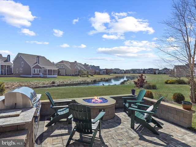 view of patio with an outdoor fire pit, a water view, a residential view, and area for grilling