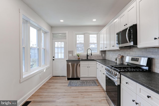 kitchen with visible vents, decorative backsplash, appliances with stainless steel finishes, light wood-type flooring, and a sink