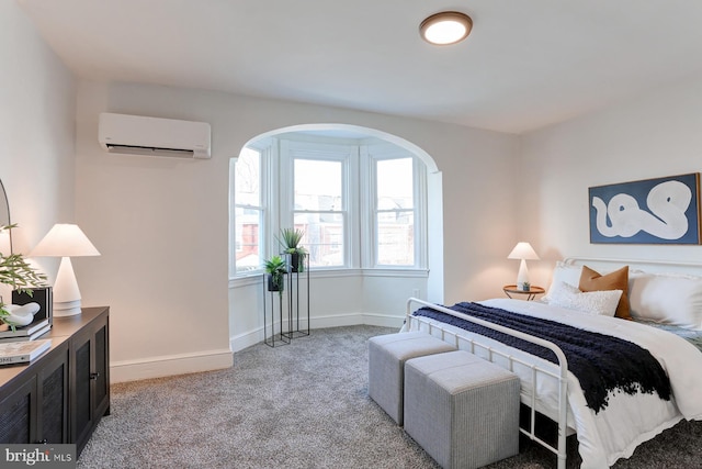 bedroom with a wall unit AC, baseboards, and light colored carpet