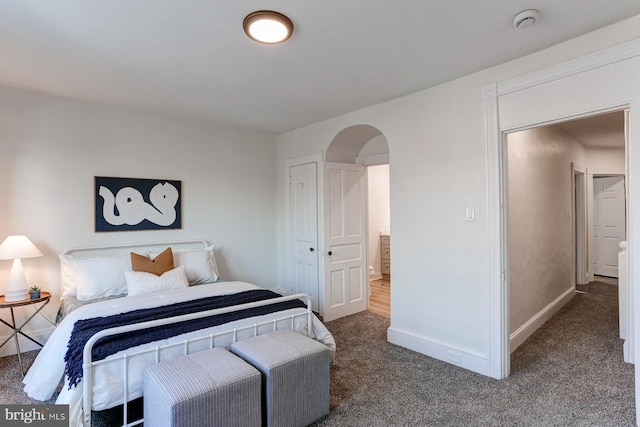 bedroom with arched walkways, carpet flooring, and baseboards