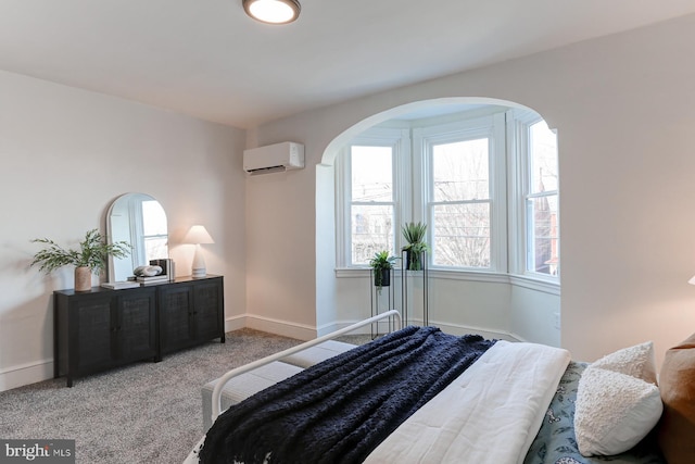 bedroom with carpet, an AC wall unit, arched walkways, and baseboards