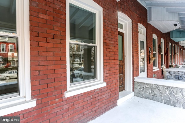 property entrance featuring a porch and brick siding