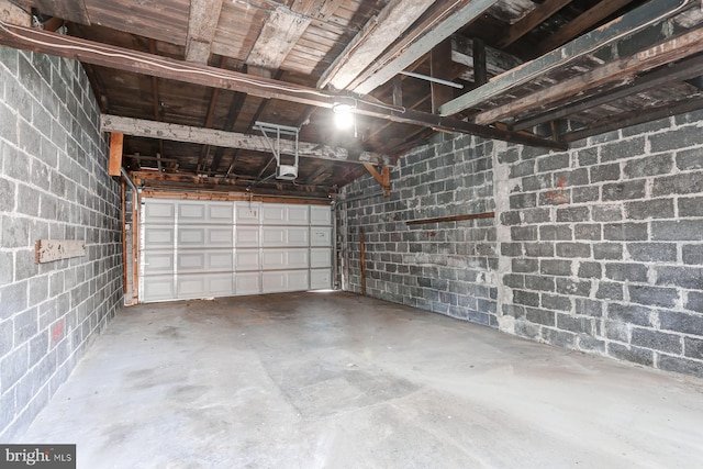 garage featuring concrete block wall and a garage door opener