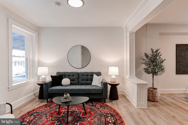 living room featuring wood finished floors, decorative columns, and baseboards