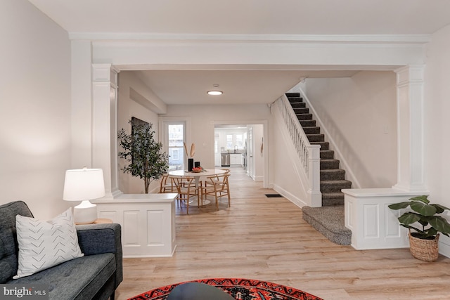 interior space featuring light wood-type flooring, decorative columns, and stairs