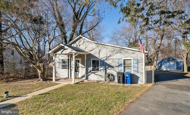 bungalow-style house with a front lawn, an outdoor structure, a garage, and driveway