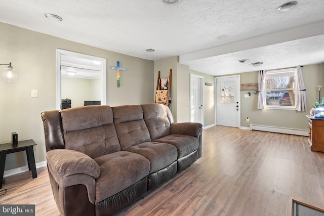 living room featuring baseboards, a textured ceiling, a baseboard heating unit, and light wood-style floors