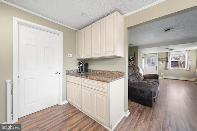 kitchen with visible vents, a baseboard heating unit, a textured ceiling, wood finished floors, and open floor plan